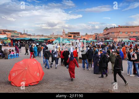 MARRAKESCH, MAROKKO - 20. FEBRUAR 2022: Menschen besuchen den Markt auf dem Jemaa el-Fnaa-Platz in Marrakesch, Marokko. Der Platz ist als UNESCO-Masterpiec gelistet Stockfoto