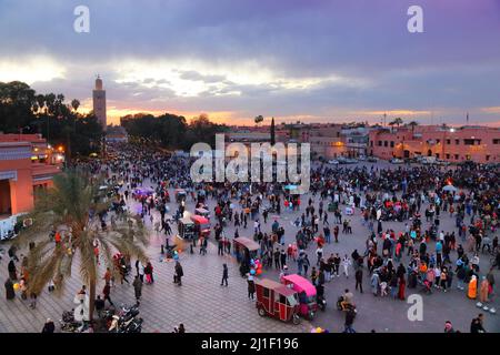 MARRAKESCH, MAROKKO - 20. FEBRUAR 2022: Menschen besuchen den Markt auf dem Jemaa el-Fnaa-Platz in Marrakesch, Marokko. Der Platz ist als UNESCO-Masterpiec gelistet Stockfoto
