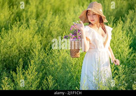 Glückliche Frau, offene Arme, die umheratmen. Freiheit Mädchen springen und genießen das Leben gegen den blauen Himmel im Blumengarten. Stockfoto
