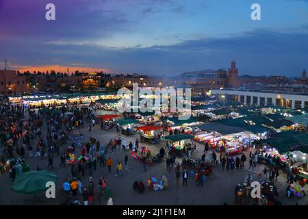 MARRAKESCH, MAROKKO - 20. FEBRUAR 2022: Menschen besuchen den Markt auf dem Jemaa el-Fnaa-Platz in Marrakesch, Marokko. Der Platz ist als UNESCO-Masterpiec gelistet Stockfoto