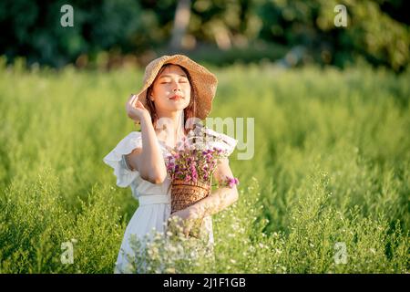 Glückliche Frau, offene Arme, die umheratmen. Freiheit Mädchen springen und genießen das Leben gegen den blauen Himmel im Blumengarten. Stockfoto