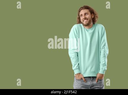 Lächelnder junger Mann im Sweatshirt auf grünem Hintergrund Stockfoto