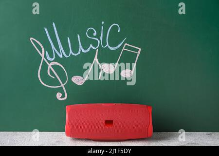 Kabelloser tragbarer Lautsprecher, mit dem Sie Musiknoten und WORTMUSIK auf grünem Hintergrund zeichnen können Stockfoto