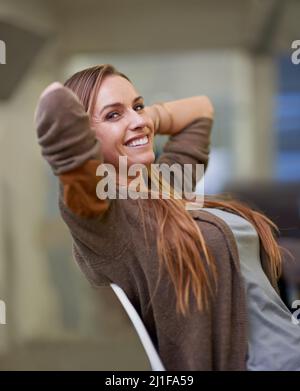 Bei der Arbeit einfach. Eine attraktive Arbeitnehmerin, die einen entspannten Tag im Büro hat. Stockfoto