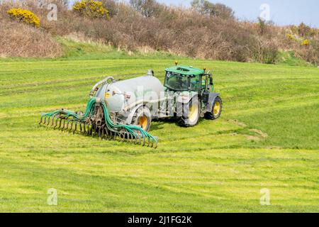 Gülle, die sich mit Tropfstangen ausbreitet, die vom Traktor auf der irischen Farm abgeschleppt werden Stockfoto