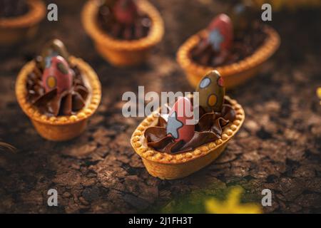Süße Törtchen mit Schokoladencreme, verziert mit Osterschokoladeneiern Stockfoto