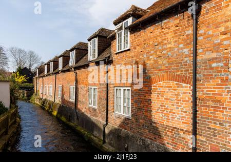 Historische Cottages aus roten Backsteinen mit Dachfenstern und gefüllten Fenstern, die auf den Fluss Dun in Hungerford, einer Stadt in der englischen Grafschaft Bekshire, blicken Stockfoto