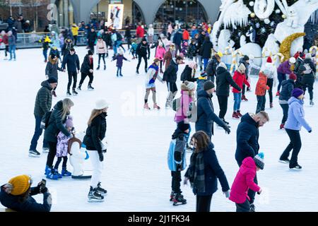 Ukraine, Kiew - 7. Januar 2022: Eislaufbahn im Winter. Die Leute laufen. Schlittschuhe fahren auf Eis. Eislaufen ist ein Wintersport-Unterhaltung. Weihnachtszeit. Weihnachtsbaum Roshen Fabrik. Menge Stockfoto