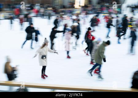 Ukraine, Kiew - 7. Januar 2022: Eislaufbahn im Winter. Die Leute laufen. Schlittschuhe fahren auf Eis. Eislaufen ist ein Wintersport-Unterhaltung. Weihnachtszeit. Weihnachtsbaum Roshen Fabrik. Menge Stockfoto