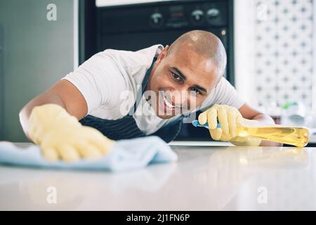 Diese Theke muss quietschend sauber sein. Aufnahme eines jungen Mannes, der zu Hause eine Oberfläche abwischt. Stockfoto