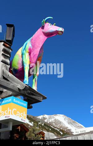 Mehrfarbige Modellkuh vor strahlend blauem Himmel: Das Logo des Restaurants Kuhtaier Dorfstadl im Skigebiet Kuhtai, Tiroler Alpen, Österreich Stockfoto