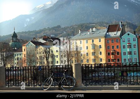Eine der berühmtesten Sehenswürdigkeiten Innsbrucks, die farbige Gebäudereihe der Inn-Salzach-Architektur am Inn, dahinter der Nordkette Stockfoto
