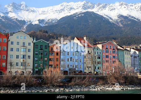 Eine der berühmtesten Sehenswürdigkeiten Innsbrucks, die farbige Gebäudereihe der Inn-Salzach-Architektur am Inn, dahinter der Nordkette Stockfoto