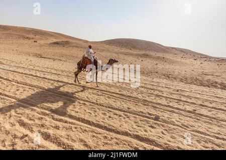 Mann, der auf einem Kamel in der Nähe der Pyramiden Ägyptens reitet Stockfoto