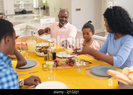 Glückliche afroamerikanische, generationsübergreifende Familie, die am Danktag zu Hause gemeinsam zu Mittag gegessen hat Stockfoto