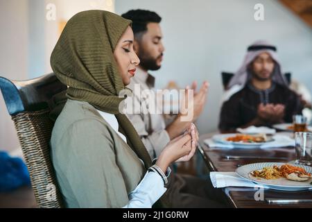 Danke für ein üppig festliches Fest. Aufnahme einer muslimischen Familie, die betet, bevor sie ihr Fasten brechen. Stockfoto