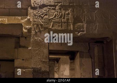 Wandschnitzereien, einschließlich des sitzenden gottes Horus, über einer Tür im Tempel von Kom Ombo, in Assuan Stockfoto