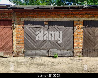 Graue Holztür zu einer alten Garage. Stockfoto