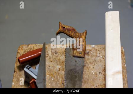Hobel, Säge und Holzblock auf einem Hocker Stockfoto