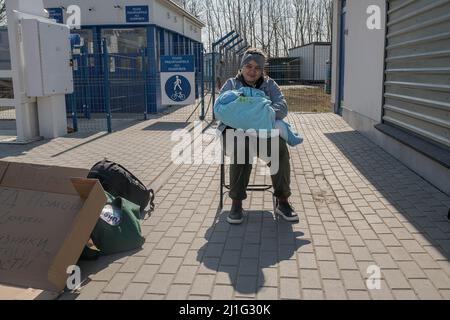 Eine junge Frau macht eine Pause, während sie ihre Tochter trägt, sie haben gerade die Grenze nach Moldawien überschritten. Palanca ist die nächste Grenze zur Stadt Odessa in der Ukraine. Diese kleine Stadt ist der letzte Punkt südlich von Moldawien vor der Überfahrt in ukrainisches Territorium. Nach Angaben der moldauischen Regierung sind seit Beginn des bewaffneten Konflikts rund 175.000 Menschen eingedrungen. Wenn Menschen in das Land einreisen, haben sie die Möglichkeit, in Flüchtlingslagern zu unterbringen, die die Regierung und internationale Organisationen für die humanitäre Notlage geschaffen haben, aber die meisten versuchen, in andere Länder zu ziehen Stockfoto