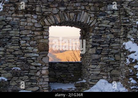 Blick auf die Landschaft durch das alte Steinfenster einer Burgruine Stockfoto