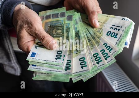 Nahaufnahme der Hände eines unbekannten kaukasischen älteren Mannes, der 100-Euro-Banknoten hält und zählt, Geldvermögenversicherungszahlungen oder lebenslange Sparungen Copy spac Stockfoto