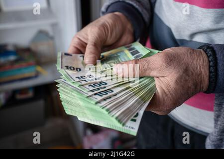 Nahaufnahme der Hände eines unbekannten kaukasischen älteren Mannes, der 100-Euro-Banknoten hält und zählt, Geldvermögenversicherungszahlungen oder lebenslange Sparungen Copy spac Stockfoto