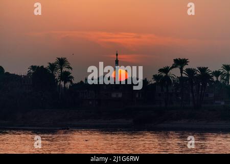 Die Sonne geht hinter dem Minarett auf dem Nil unter Stockfoto