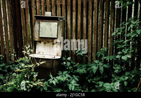 In einem Grasdickicht steht ein altes und rostiges sowjetisches Straßenwaschbecken Stockfoto