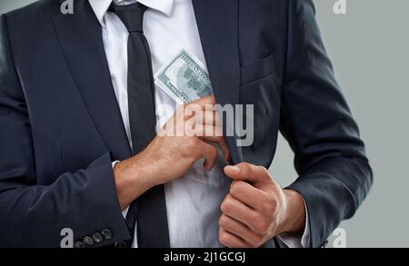 Die wirklichen Verbrecher tragen Anzüge, keine Balaclavas Zugeschnittenes Bild eines Geschäftsmannes, der Geld in die Tasche steckte. Stockfoto