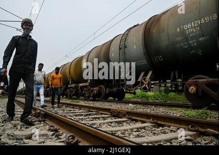 Rajpur Sonarpur, Westbengalen, Indien. 25. März 2022. Männer laufen am 25. März 2022 an einem Öltanker-Zug vorbei, der an einem Bahnhof am Stadtrand von Kalkutta stationiert ist. Kredit: ZUMA Press, Inc./Alamy Live Nachrichten Stockfoto