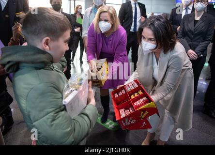 Frankfurt, Deutschland. 25. März 2022. 25. März 2022, Hessen, Frankfurt/Main: Bundesaußenministerin Annalena Baerbock (Bündnis 90/die Grünen, r) und Bundesinnenministerin Nancy Faeser (SPD) geben Flüchtlingskindern Süßigkeiten. Die Flüchtlinge waren aus Moldawien, einem Nachbarland der Ukraine, geflogen. Quelle: dpa picture Alliance/Alamy Live News Stockfoto