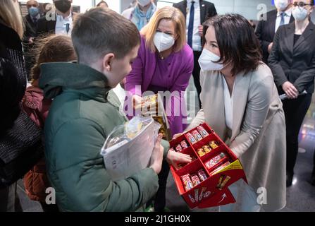 Frankfurt, Deutschland. 25. März 2022. 25. März 2022, Hessen, Frankfurt/Main: Bundesaußenministerin Annalena Baerbock (Bündnis 90/die Grünen, r) und Bundesinnenministerin Nancy Faeser (SPD) geben Flüchtlingskindern Süßigkeiten. Die Flüchtlinge waren aus Moldawien, einem Nachbarland der Ukraine, geflogen. Quelle: dpa picture Alliance/Alamy Live News Stockfoto