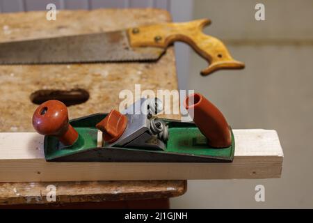 Hobel, Säge und Holzblock auf einem Hocker Stockfoto