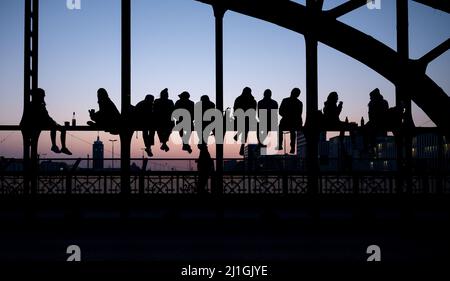München, Deutschland. 25. März 2022. Zahlreiche Menschen genießen das schöne Wetter auf der Hackerbrücke und beobachten den Sonnenuntergang. Quelle: Sven Hoppe/dpa/Alamy Live News Stockfoto
