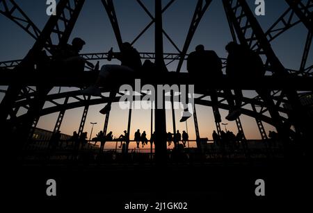 München, Deutschland. 25. März 2022. Zahlreiche Menschen genießen das schöne Wetter auf der Hackerbrücke und beobachten den Sonnenuntergang. Quelle: Sven Hoppe/dpa/Alamy Live News Stockfoto