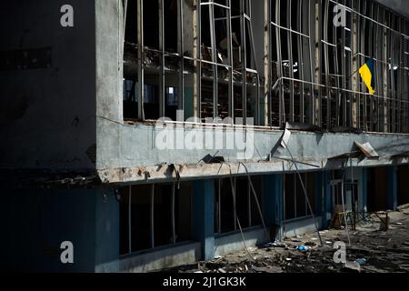 Charkiw, Ukraine. 25. März 2022. An der Wand einer Schule, die kürzlich von einem russischen Streik in Charkiw, Ukraine, am 25. März 2022 getroffen wurde, ist eine ukrainische Flagge befestigt. Gestern tötete der russische Beschuss sechs Menschen, die vor einem Postamt auf Hilfsgüter warteten, und heute riss der russische Beschuss eine Pipeline und löste ein massives Feuer in der Nähe des Marktes Barabashovo aus. Kredit: ZUMA Press, Inc./Alamy Live Nachrichten Stockfoto