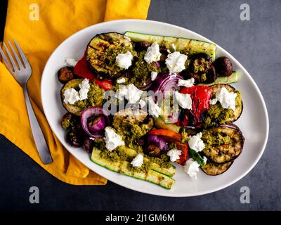 Blick von oben auf gegrillten Gemüsesalat mit Ziegenkäse und Pesto: Gegrillte Auberginen, Zucchini, Zwiebeln, Pilze und rote Paprika Stockfoto