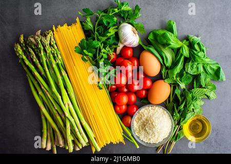 Toskanische Linguine Pasta all'Etrusca mit Spargel Zutaten: Rohes Gemüse, Kräuter, Pasta, Eier und andere Zutaten von oben gesehen Stockfoto