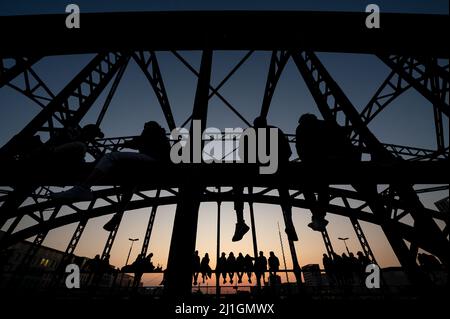 München, Deutschland. 25. März 2022. Zahlreiche Menschen genießen das schöne Wetter auf der Hackerbrücke und beobachten den Sonnenuntergang. Quelle: Sven Hoppe/dpa/Alamy Live News Stockfoto