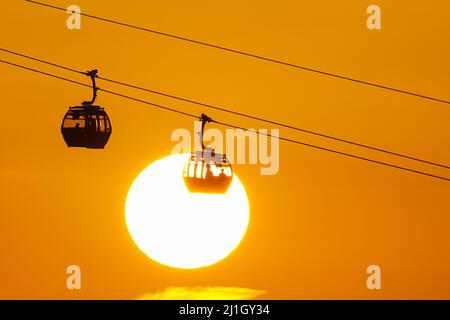 Die Sonne geht hinter dem IFS Cloud Cable Car in London, England, Großbritannien unter Stockfoto