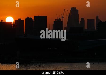 London, Großbritannien. 25. März 2022. Wetter in Großbritannien: Die Sonne geht hinter den Wolkenkratzern der City of London unter. Quelle: Marcin Rogozinski/Alamy Live News