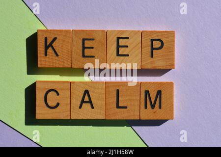 Halten Sie sich ruhig, Wörter in hölzernen Buchstaben auf pastellfarbenem Hintergrund isoliert Stockfoto