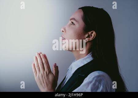 Junge Brünette Mädchen beten zu gott, Nahaufnahme Porträt. Frau faltet ihre Hände im Gebet. Glaube und Hoffnung Konzept. Stockfoto