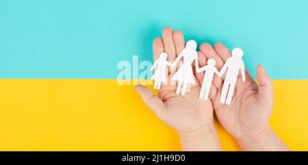 Eltern mit zwei Kindern, die Hände halten, Familienleben, ausgeschnittenes Papier, Kopierraum, gelber und blauer Hintergrund, Beziehung Stockfoto