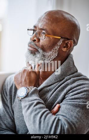 Er verbringt viel Zeit tief in Gedanken. Aufnahme eines gutaussehenden älteren Mannes, der nachdenklich aussieht, während er sich zu Hause entspannt. Stockfoto