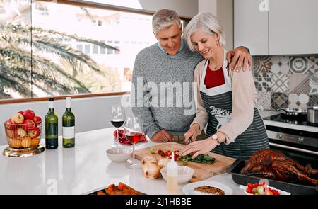 Sie prahlt mit dem besten Braten. Aufnahme eines reifen Paares, das zu Hause ein Thanksgiving-Essen zubereitet. Stockfoto