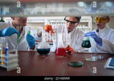 Junge Chemiestudenten mischen in einer Arbeitsatmosphäre im Universitätslabor bunte Chemikalien und beobachten chemische Reaktionen. Wissenschaft, Chemie, Stockfoto