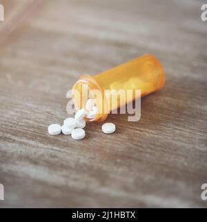 Wie viele Schmerzmittel sind zu viele. Aufnahme einer Flasche Pillen, die tagsüber auf einem Tisch in einem Wohnzimmer offen lag. Stockfoto