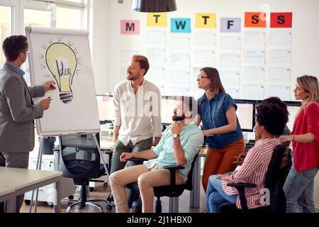 Eine Gruppe junger Mitarbeiter verfolgt einen Vortragsvortrag bei einem Treffen in einer Arbeitsatmosphäre im Büro. Mitarbeiter, Job, Büro Stockfoto